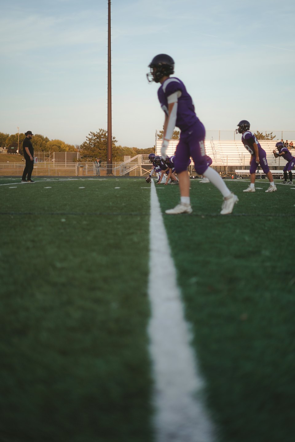 Youth football players practice on a green turf field.
